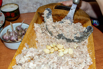 An old Russian recipe for making meat jelly. Women chopping meat for aspic in an old trough. Preparing for the holiday in Russia.