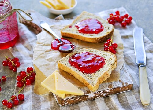 Crispy toast of wheat bread with red currant jam on a wooden board