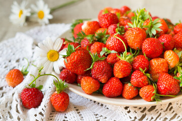 Ripe red strawberries on a plate with daisies

