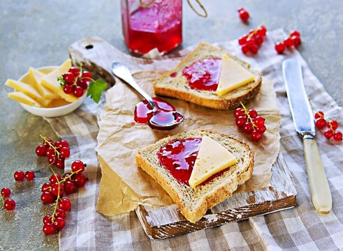Crispy toast of wheat bread with red currant jam on a wooden board