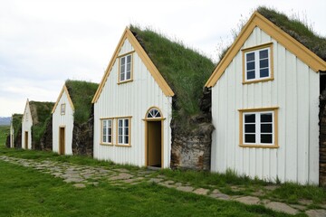 Fototapeta na wymiar Mit Torf erbaute und isolierte Häuser auf Island. Die mit dünnen Brettern und 60 cm dicken Torf erbauten Häuser bieten eine hervorragende Wärmeisolation. Die Torfschicht des Daches ist grasbewachsen.