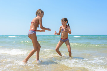 Two girls playing fight on the seashore in the water