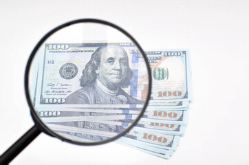 Magnifying glass and dollars on a white background. 100 dollars banknote view through a magnifying glass