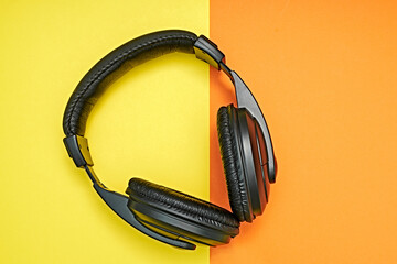Large, black headphones lie on a colored background. Device for individual listening to music.