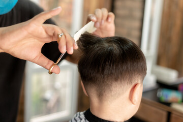 little boy hair with an electric clipper, in barber shop