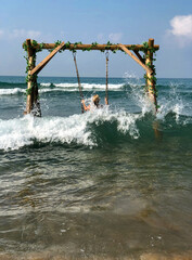 The girl in the hat is covered by a wave in the sea. Large sea swing.