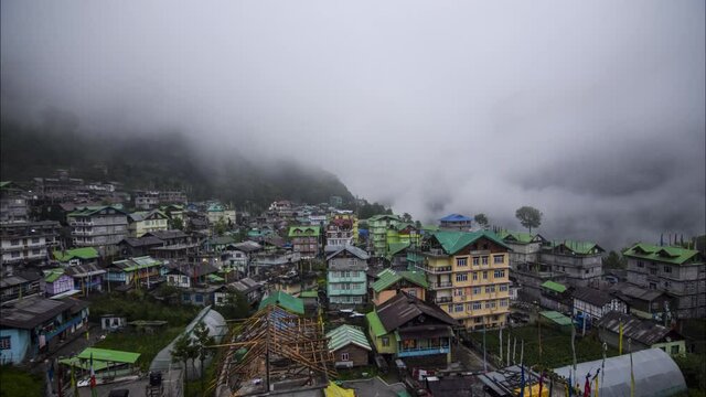 Time-lapse of moving clouds in the evening covering the entire city constructed inside a valley surrounded by mountains in the Northern parts of Sikkim named Lachen shot in 4k