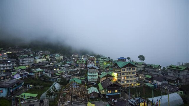 Time-lapse of moving clouds covering the entire city constructed inside a valley surrounded by mountains in the Northern parts of Sikkim named Lachen changing from evening to night shot in 4k.