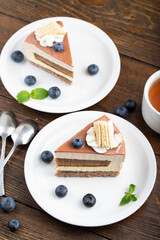 Slice of cheese cake with blueberries on a brown wooden background