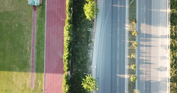 Aerial view of the running track and city road. training people and passing cars can be seen