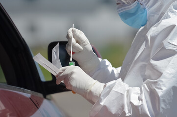 Unrecognizable people wearing protective suit handles a pharyngeal exudate/ swab collection kit for the coronavirus. Test tube for taking OP NP patient specimen sample, PCR DNA testing