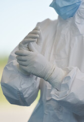 Unrecognizable people wearing protective suit handles a pharyngeal exudate/ swab collection kit for the coronavirus. Test tube for taking OP NP patient specimen sample, PCR DNA testing