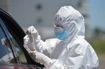 Unrecognizable people wearing protective suit handles a pharyngeal exudate/ swab collection kit for...