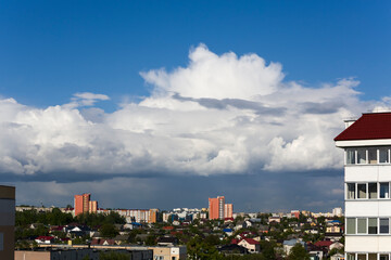 View from the height of the building to the summer, sunny city with blue sky and clouds.