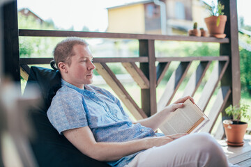 A man reads a book on the veranda.