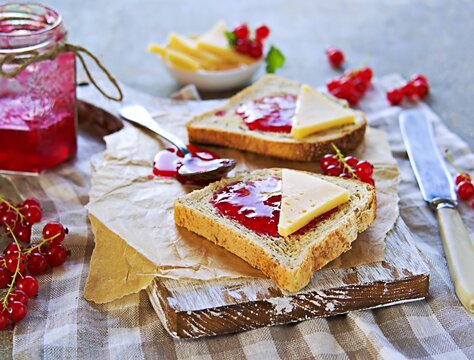 Crispy toast of wheat bread with red currant jam on a wooden board