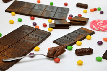 beautiful image different sweets dark chocolate and candies and lollipops and multicolored dragees on a white backgroun