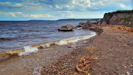 Algae and stones are on the beach and in the water. Beautiful riverside with small stones and sand after heavy rain.