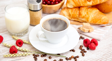 Breakfast in the morning with black coffee cup with bread with Croissant and fruit on the wooden table.