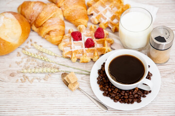 Breakfast in the morning with black coffee cup with bread with Croissant and fruit on the wooden table.