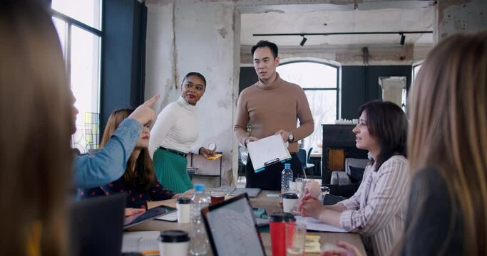 Healthy workplace concept. Young confident Asian boss businessman leading team meeting at loft trendy office slow motion