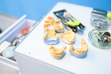 Naklejka na ściany i meble Different professional dental equipment, instruments and tools in a dentists stomatology office clinic on a white background. Silicone cast of the jaw.
