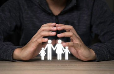 Hand protect virtual white family icon on wooden table. Lovely and take care family concept.