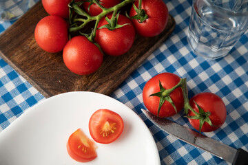 Fresh red tomatoes with water drops on a table covered with a blue tablecloth