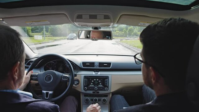 Elderly man learns to drive a car with personal instructor. Aged pensioner passing driving licence exam test on large parking space. Trip. Transportation.