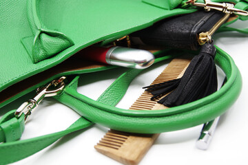 Things from lady purse isolated on white background. Cosmetics and women's accessories fell out of green handbag. Notebook, wooden comb, lipstick, brown scarf, black wallet