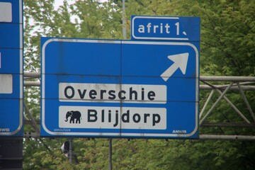 Direction sign in blue and white heading Rotterdam overschie and Blijdorp Zoo on motorway A13.