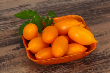 Yellow tomato heap in the wooden bowl