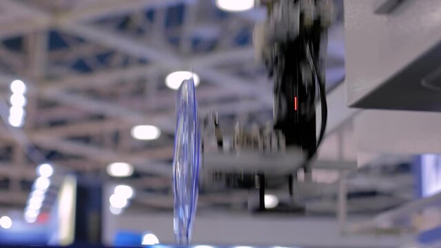 Automatic pick and place robotic arm manipulator with suction cups moves container lids, covers - part of plastic injection molding machine at exhibition, trade show. Manufacturing, production concept