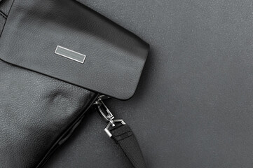 Men's black leather bag on black background. close up. Space for text.