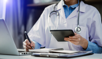 Medical technology concept. Doctor working with mobile phone and stethoscope and digital tablet laptop in modern office at hospital in morning light

