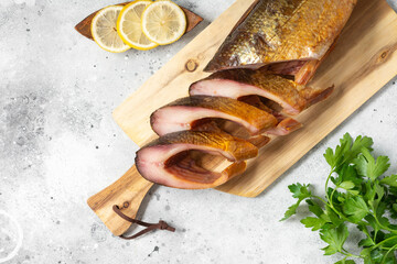 Smoked fish omul. Smoked fish steaks on a serving Board. Sliced smoked omul fish on the light gray kitchen table. Fish close-up. Top view with space for text