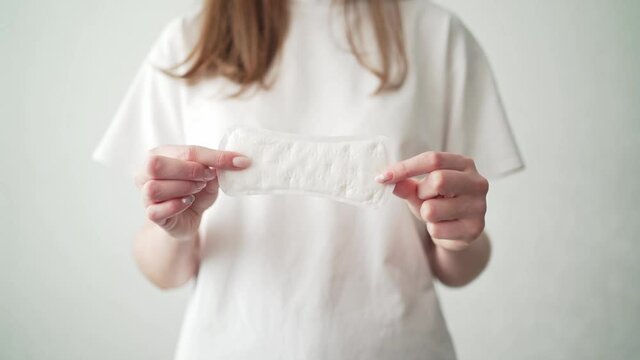 A woman with a period holds a white pad. Taking care of women's health. Hygiene during menstruation