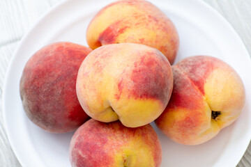 A few ripe peaches lie on a plate