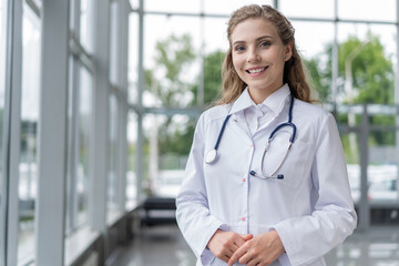 Portrait of young woman doctor with white coat standing in hospital.