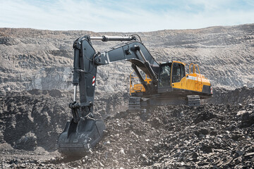 Yellow big excavator in the coal mine, loads the breed, with the bright sun and nice blue sky in the background. Mining truck mining machinery. Technique in coal mine © timofeev