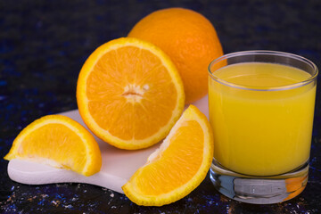 Fototapeta na wymiar A glass of fresh orange juice on a dark blue background.