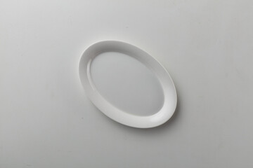 Fototapeta premium Top view shot of an oval plate on white background.