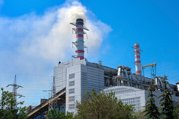 Obraz premium Thermal power plant, industrial chimney against a clear blue sky.