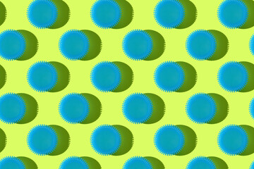 Colorful seamless pattern: blue plastic bottle caps on yellow background with hard shadow, flat lay