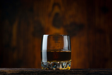 A glass of cognac on the table. Old wooden background.
