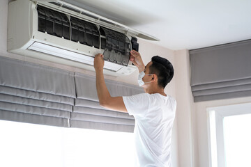 Fototapeta na wymiar Technician man repairing ,cleaning and maintenance Air conditioner on the wall in bedroom or office room.On site home service,Business ,Industrial concept.