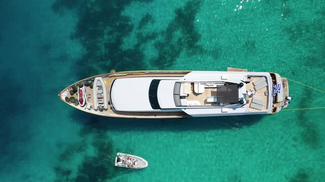 Aerial drone top down video of luxury yacht anchored in Mediterranean bay with emerald sea