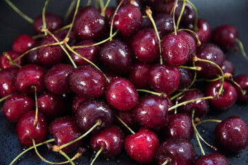 Red fresh cherries on a black background. Drop of water. Close up. The concept of freshness.