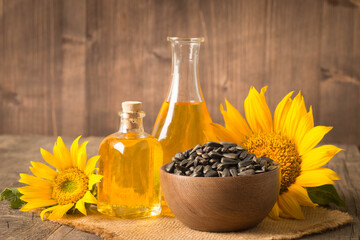 Closeup photo of sunflower oil with seeds on wooden background. Bio and organic product concept.