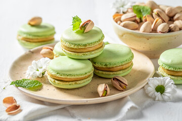Delicious pistachio macaroons on wooden table with flowers